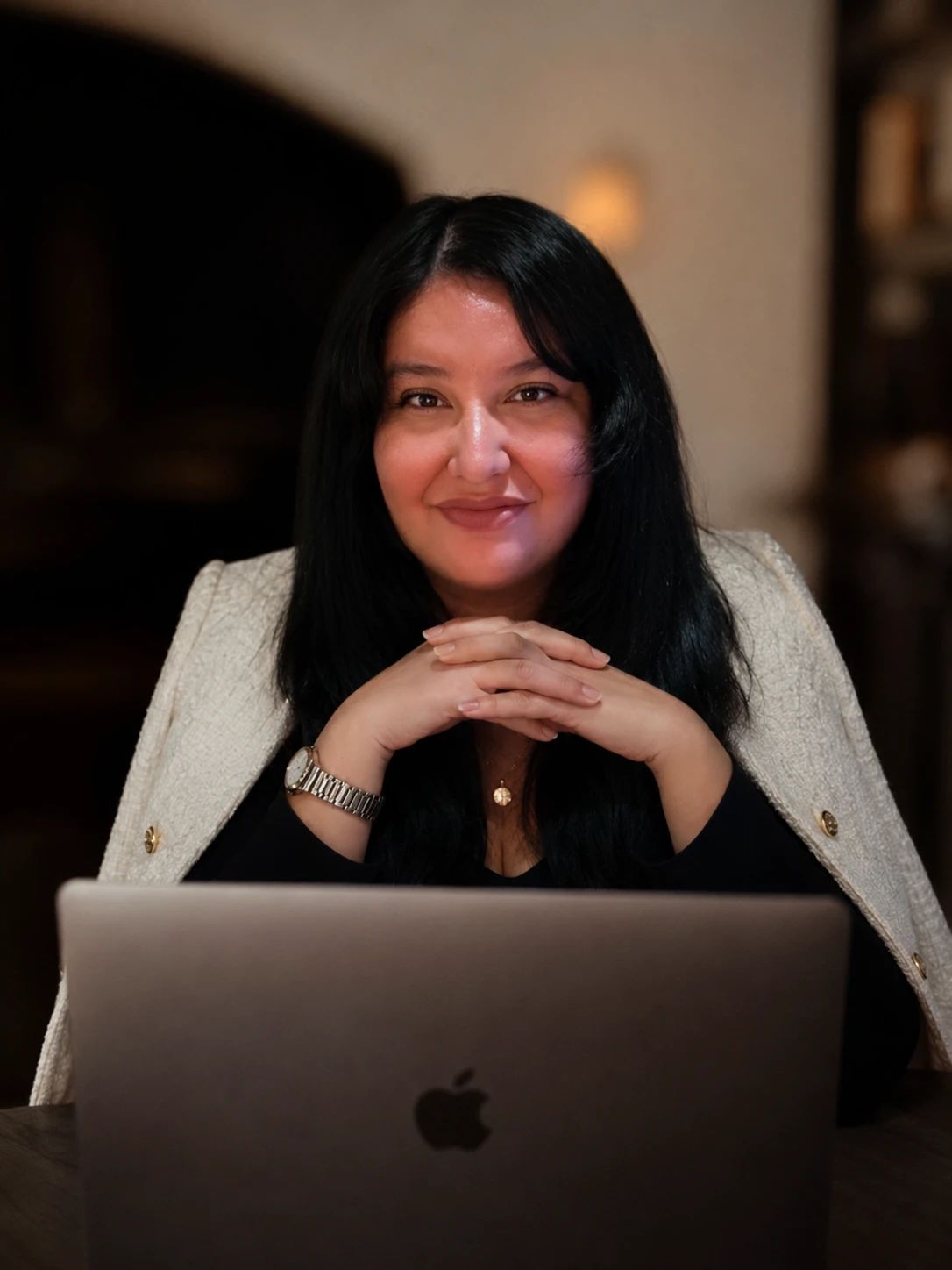 Lorena Tigani sentada frente a su computadora, con las manos entrelazadas y una sonrisa serena